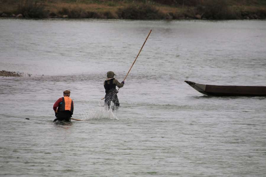 水面を棒で叩きながら小回し舟に近づいて行く漁師